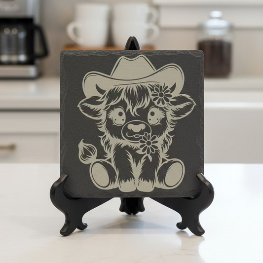Slate coaster with a printed design of a cow wearing a cowboy hat on a white background